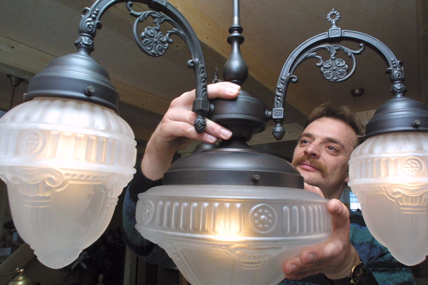 Geschäftsinhaber Holger Henschel von Lampen der anderen Art bei der Montage eines Kronleuchters