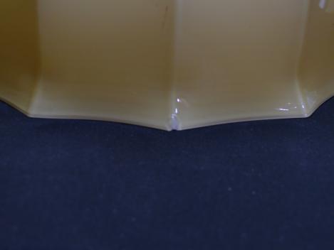 Jugendstil Lampenschirm gebraucht, Glas gelb außen, innen weiß, an den Schirmhals angrenzender flacher Absatz, daran anschließend vertikal gekniffene Wandung, eingeschnürter Rand, Detail Abplatzer Ecke
