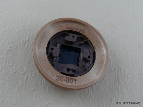 Preview: Garby Aus-Wechsel Porzellandrehschalter schwarz im Einfachrahmen Massivholz Buche honigfarben, von hinten