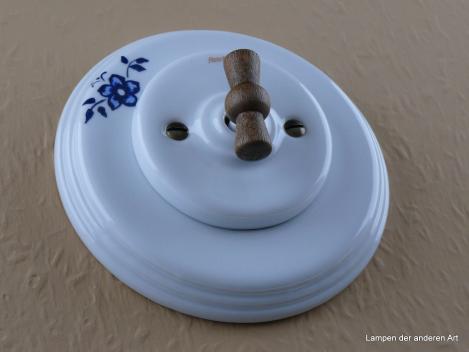 Preview: Garby Colonial Aus-Wechsel Porzellandrehschalter weiß im Einfachrahmen Porzellan weiß mit einzelnem Blumendekor Knebel Holz Buche gealtert von vorn