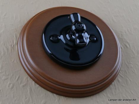 Preview: Garby Colonial Aus-Wechsel Porzellandrehschalter schwarz im Einfachrahmen Holz Buche honigfarben Knebel Porzellan schwarz von vorn