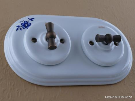 Preview: Garby Colonial 2fach Kombination, 2fach Rahmen Porzellan weiß, Dekor Blume blau, zwei Aus-Wechsel-Porzellandrehschalter weiß,  Knebel Messing patiniert