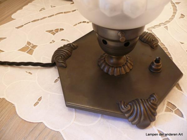 Art Deco Tischleuchte restauriert, Messing dunkel patiniert, sechseckige Gundplatte mit drei rocailleförmigen Füßen, Schirmhalterung mit Belüftungslöchern, gerader zylindrischer Schirm, grau satiniert, längsgerieft, schwarzes Textilkabel, Detail Fuß